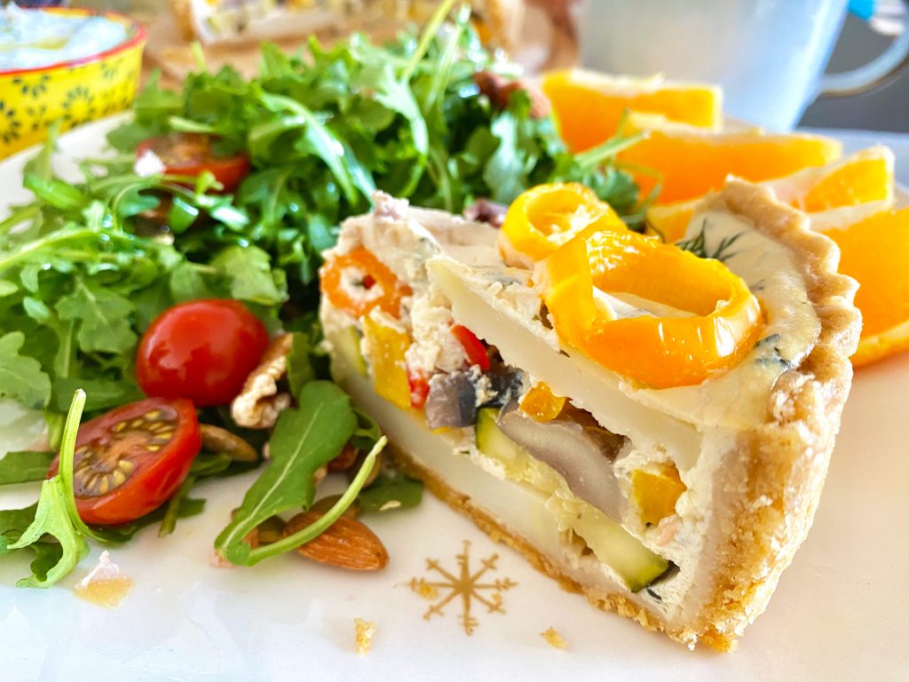 A slice of vegan roasted veggie quiche with salad A slice of vegan roasted veggie quiche with salad