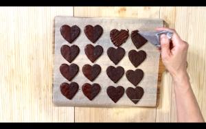 Pipe melted chocolate on cookies
